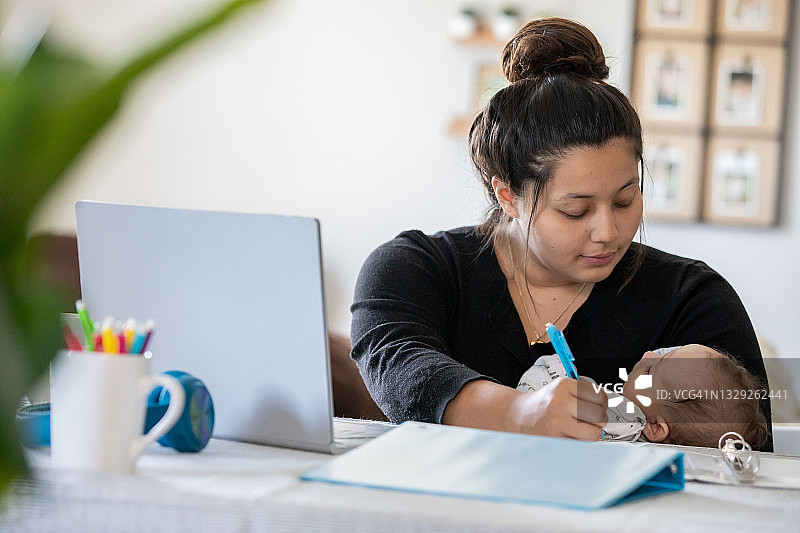 年轻母亲在家工作时照顾宝宝图片素材