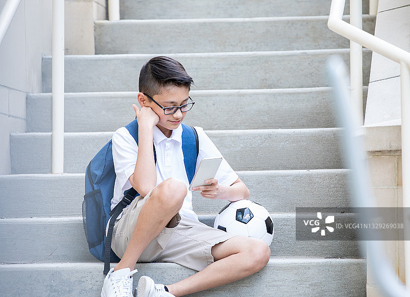 悲伤的少年在智能手机上查看社交媒体图片素材