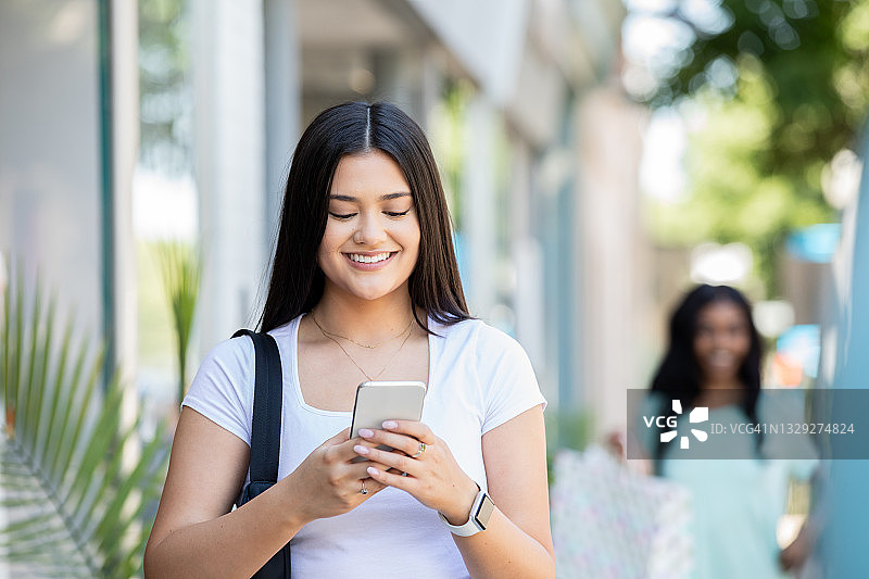 年轻女子在市中心使用智能手机查找商店图片素材