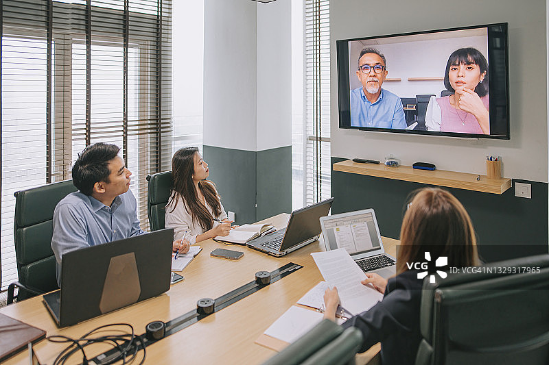 亚洲白领在董事会议室与公司员工进行视频会议图片素材