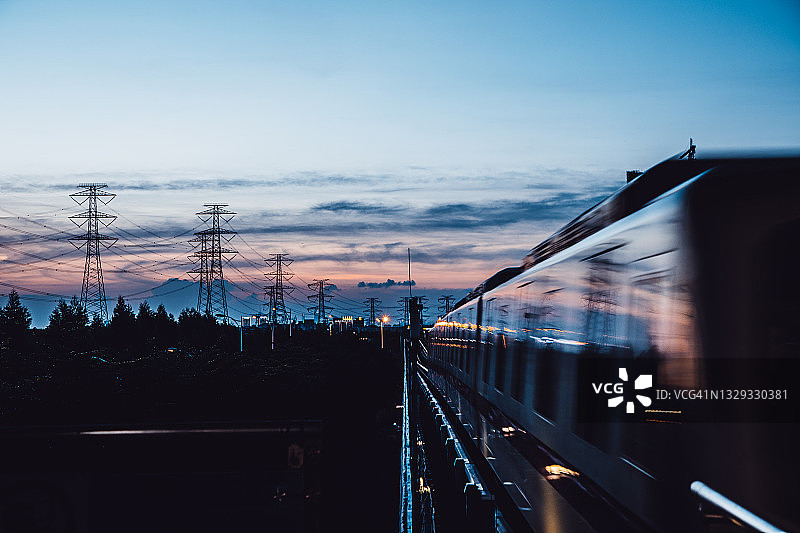 黄昏时离开/接近车站站台的高架地铁列车图片素材