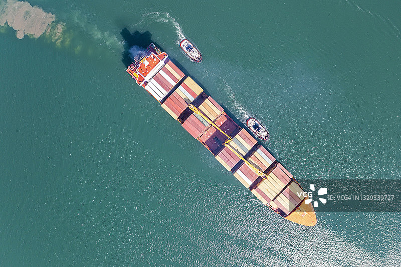 货船在拖船的协助下驶入港口的空中视角图片素材