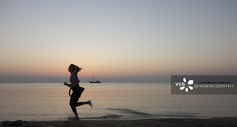 日出时在海滩慢跑的人图片素材