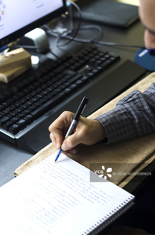 年长的男人使用电脑并做笔记图片素材