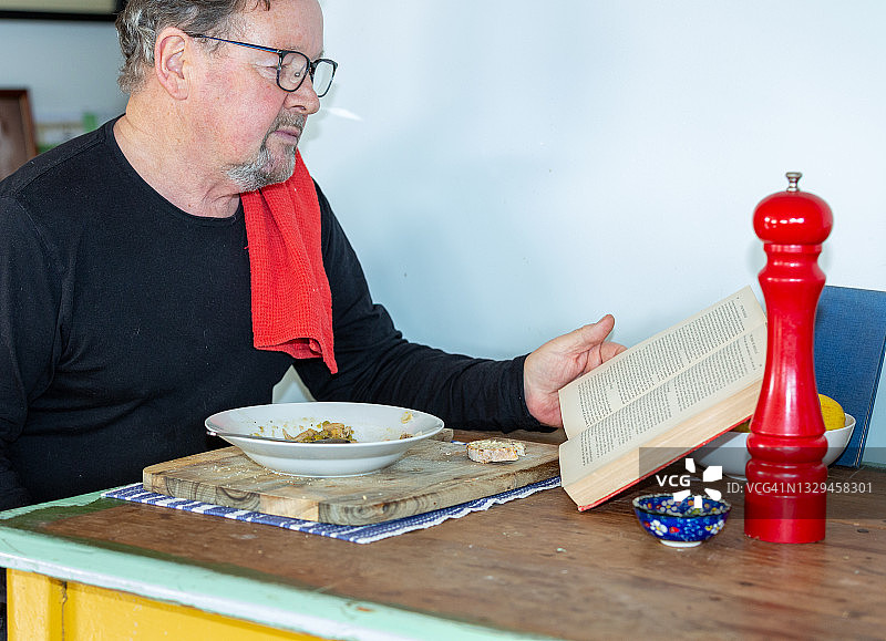 年长的男人在午餐时读书图片素材