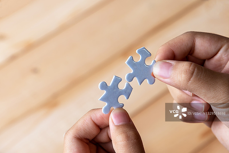 双手拼合两块小拼图——连接概念图片素材