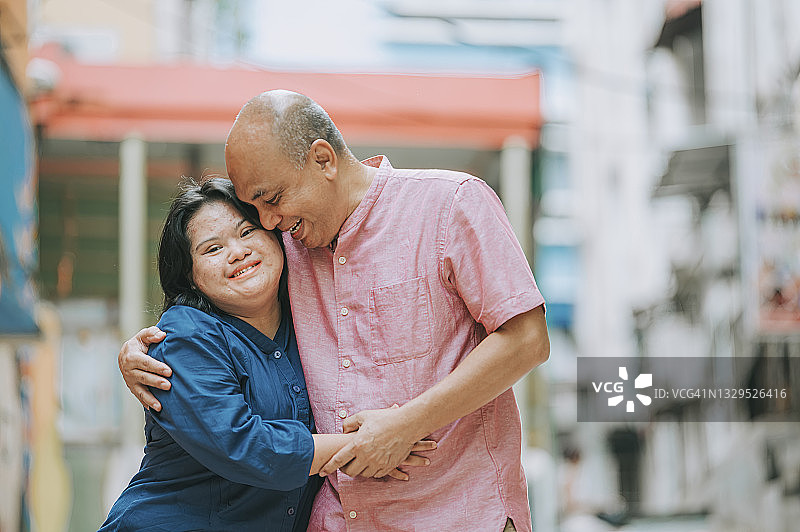 快乐的亚洲马来西亚自闭症唐氏综合征女孩与父亲在城市街道上互动图片素材