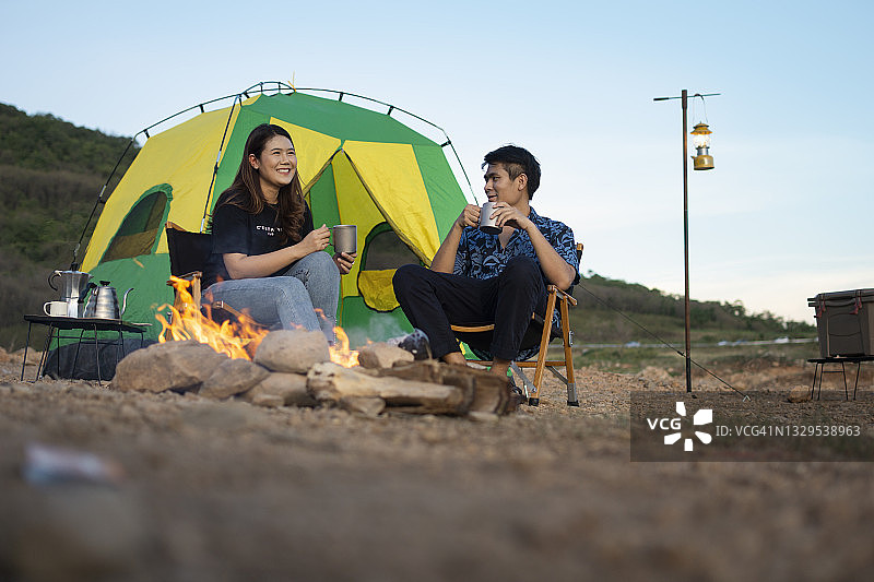 爱达荷州年轻情侣帐篷旁篝火边欢笑图片素材
