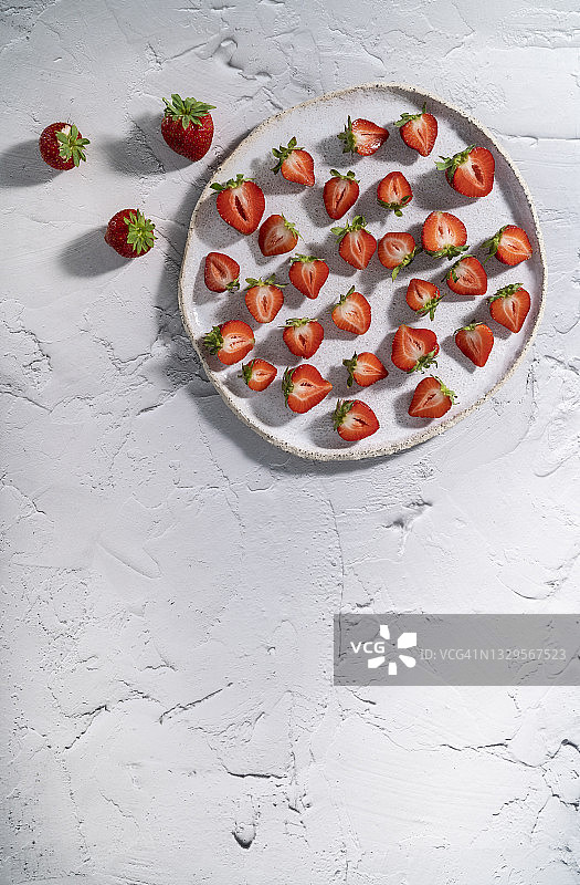 白色盘子上切半的草莓果实，乡村风格背景图片素材