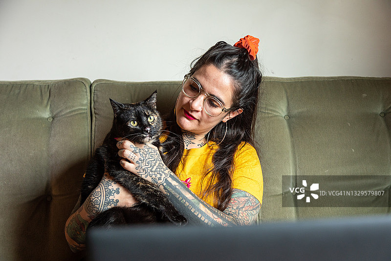 纹身女人坐在沙发上抱着猫图片素材