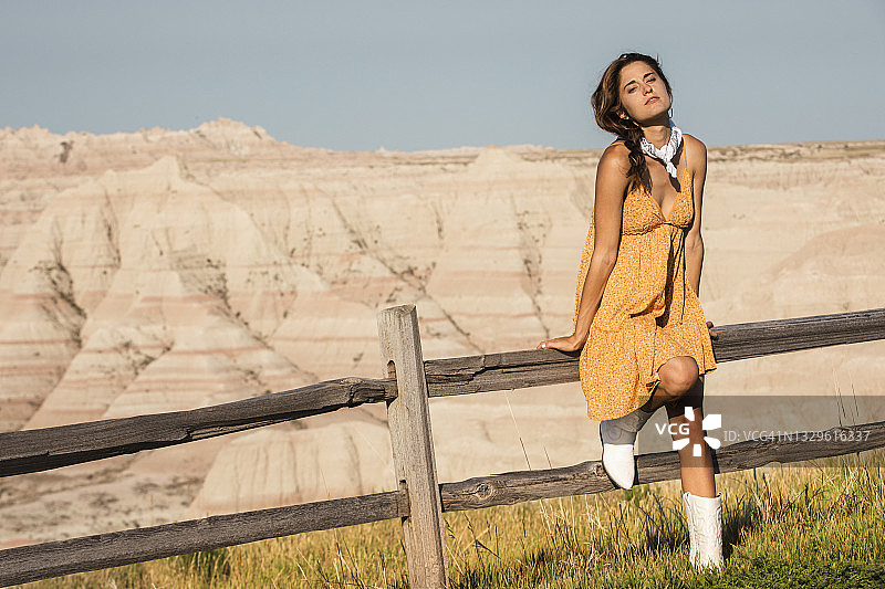 美女靠在干旱沙漠景观前的栅栏上图片素材