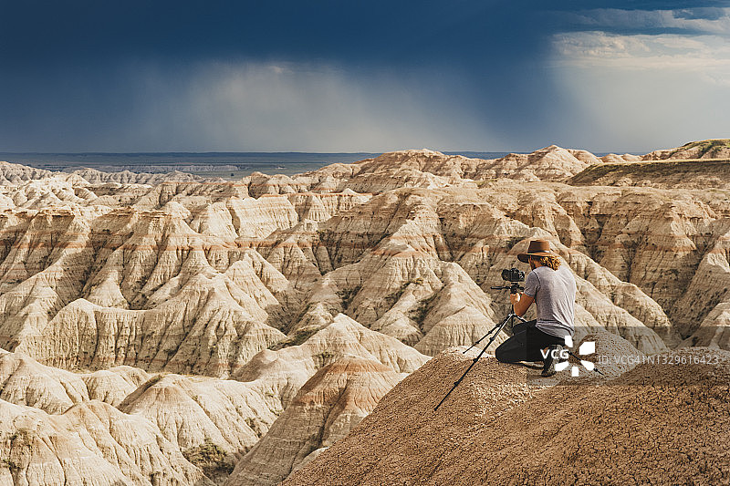 男人拍摄暴风雨天空下灯火通明的峡谷图片素材