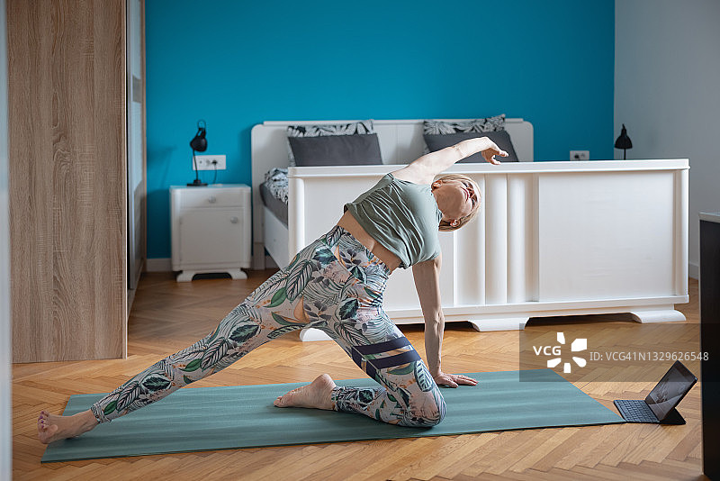 在家观看教程做侧板式瑜伽变体的女人图片素材