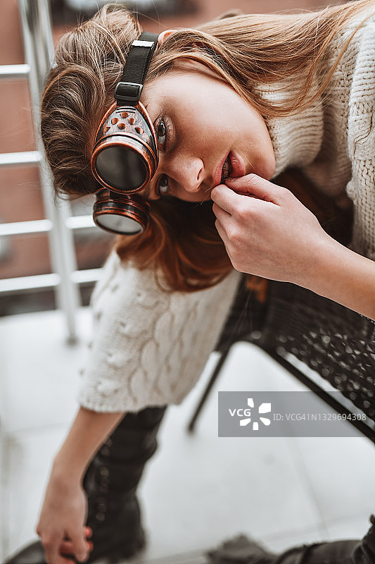 戴着蒸汽朋克护目镜在阳台上放松的美丽女人图片素材