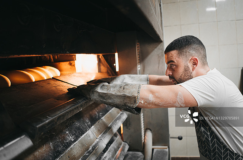 面包师在他的面包店烤面包图片素材