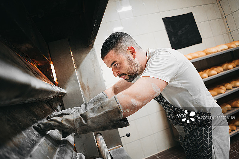 面包师在他的面包店烤面包图片素材