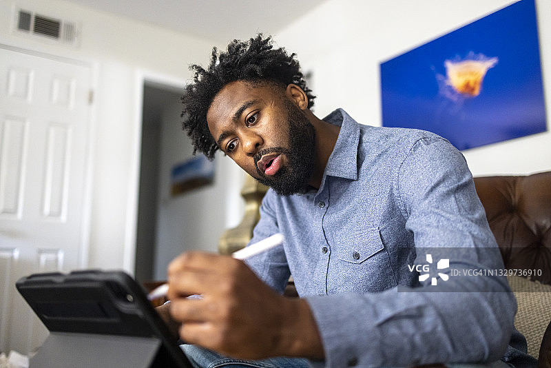 用手写笔在平板电脑上绘画的年轻黑人男子图片素材