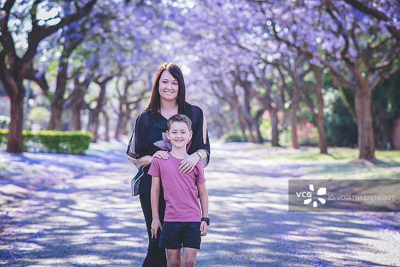 母子在紫色鲜花盛开的街道上相拥而立图片素材