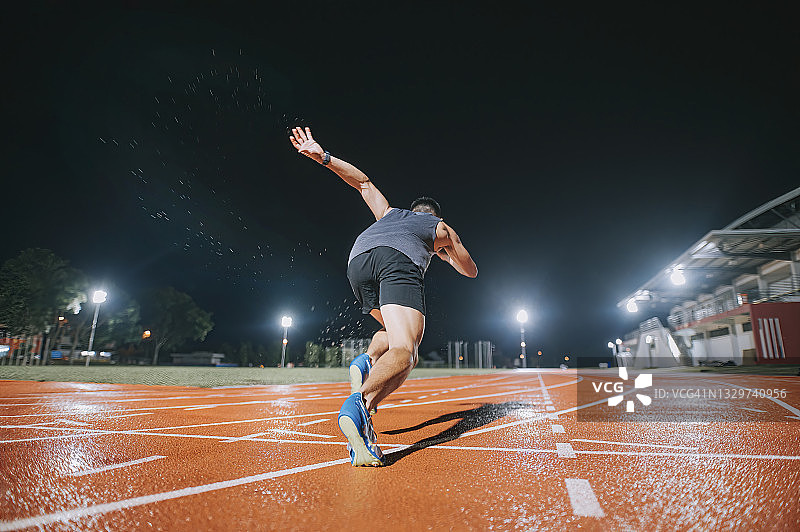 雨夜，中国男运动员在田径场冲刺图片素材