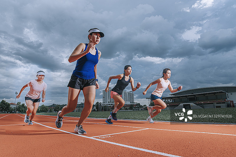 在田径体育场跑步的亚洲女运动员图片素材