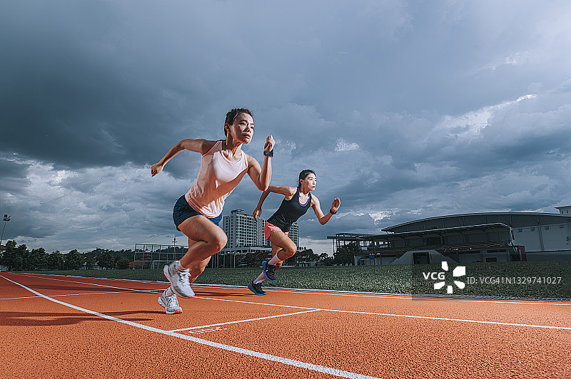 在田径体育场跑步的亚洲女运动员图片素材