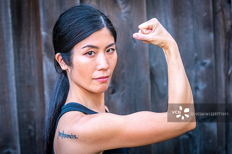 看着镜头的亚洲中年妇女展示手臂肌肉图片素材