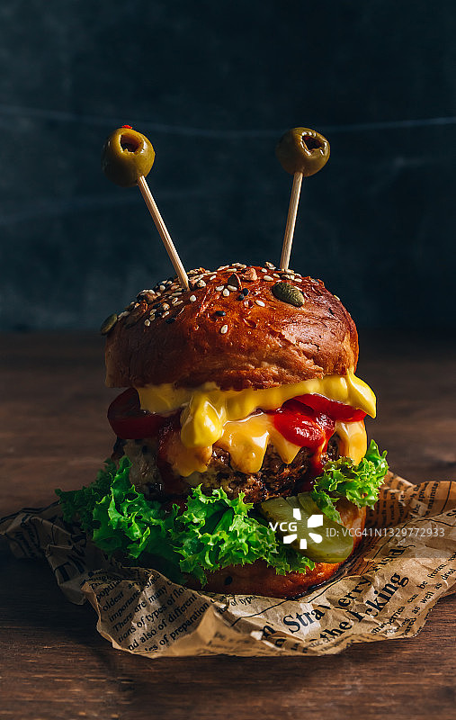 有趣的怪兽鸡肉汉堡，配有沙拉、番茄、黄瓜、奶酪和橄榄眼图片素材