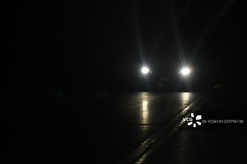 黑暗道路上行驶的车辆前灯图片素材