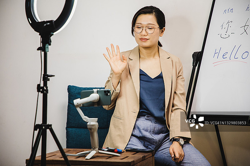 亚洲女人在三脚架上通过手机直播教中文图片素材