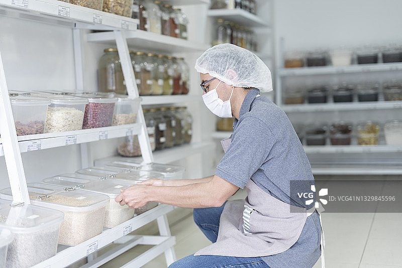 拉丁裔男子在食品杂货公司工作，以有组织的方式在货架上安排产品以供出售图片素材