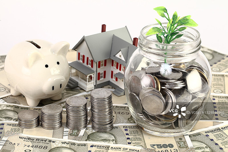 印度货币纸币上叠放的硬币和模型房图片素材