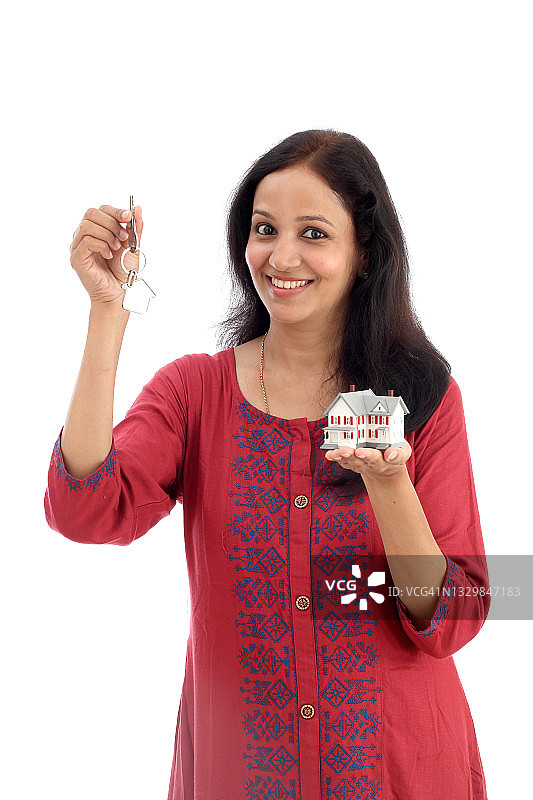 快乐的年轻女人手持钥匙和房屋模型，背景为白色图片素材