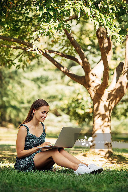女人坐在公园里使用笔记本图片素材