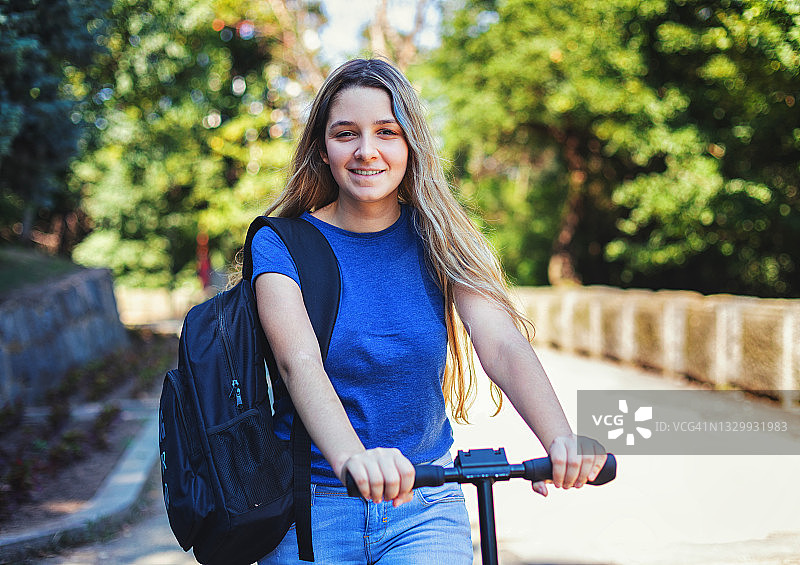 戴着口罩骑滑板车去学校的女学生图片素材