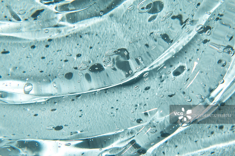 凝胶霜的纹理：蓝色背景上的液态透明质酸凝胶图片素材