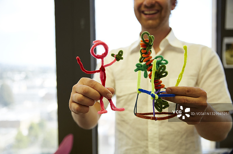 拿着植物的粉色管道清洁器小人，背景是微笑的男人图片素材