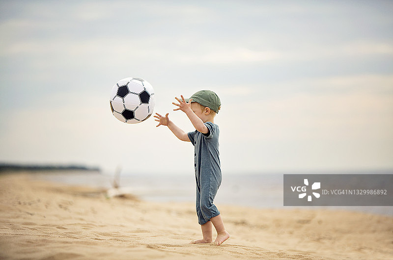 在海滩玩球的小男孩图片素材