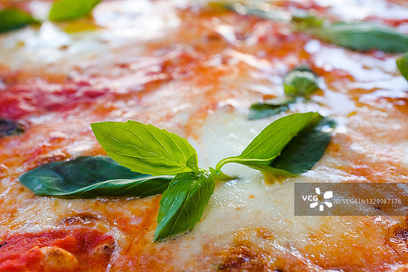 木制支架或砧板上的圆形玛格丽特披萨，配以马苏里拉奶酪和罗勒叶，在咖啡馆或快餐店的桌子上。传统的意大利美食。素食。图片素材