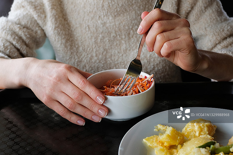 女人在咖啡馆享用经济实惠的午餐：炸土豆和卷心菜沙拉图片素材
