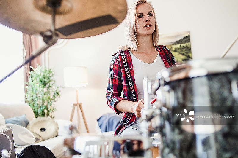 一位穿着休闲服装的年轻女子在她的公寓里演奏原声鼓图片素材