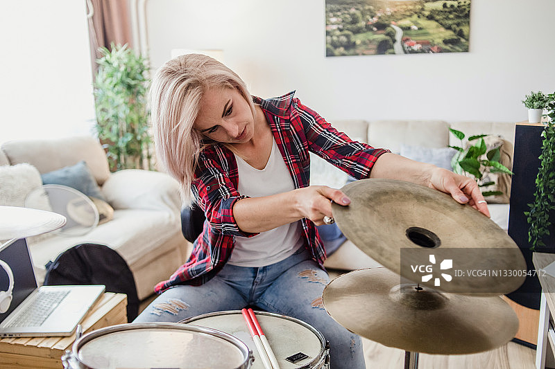 一位穿着休闲服装的年轻女子在她的公寓里演奏原声鼓图片素材