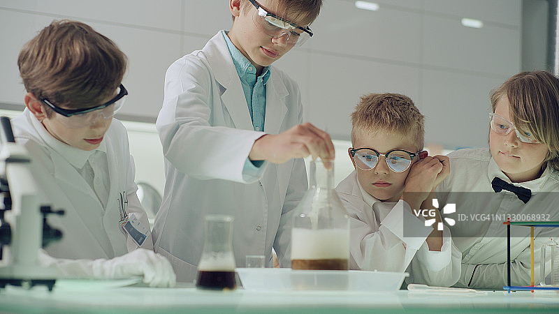 好奇的男孩在实验室里做科学实验，液体沸腾起泡图片素材