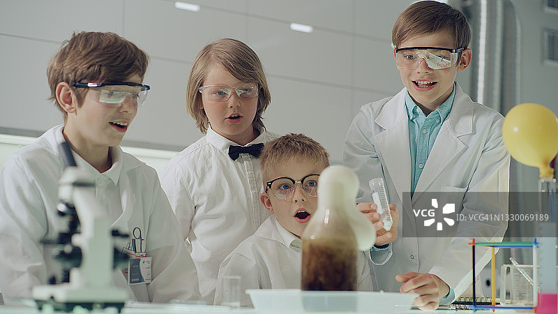 好奇的男孩在实验室里做科学实验，液体沸腾起泡图片素材