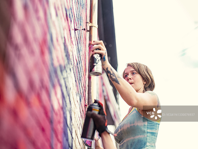 年轻女人在房子上画壁画图片素材
