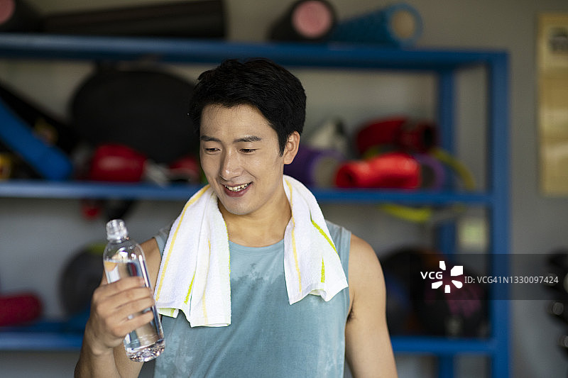 年轻的运动员男人在健身房喝水图片素材