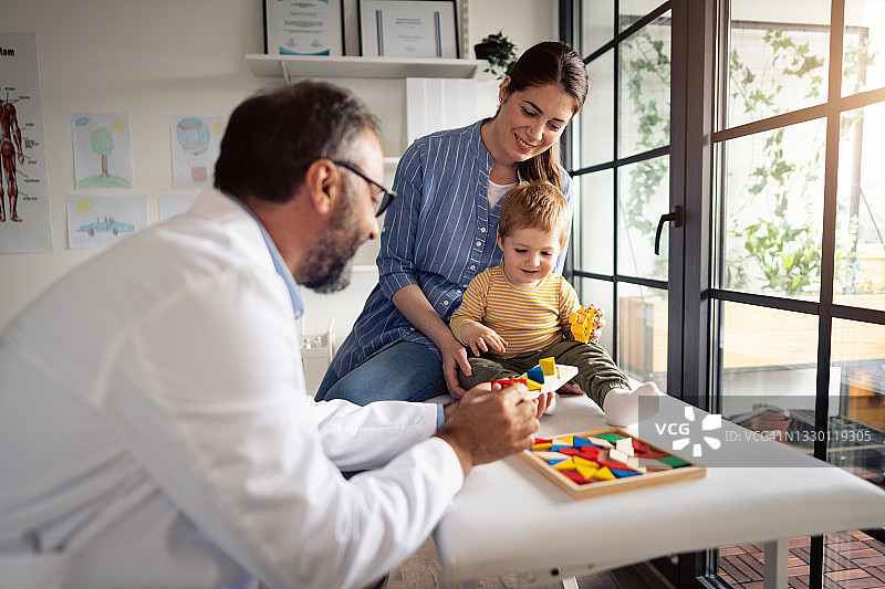 男医生和坐在桌子上的男婴玩耍图片素材