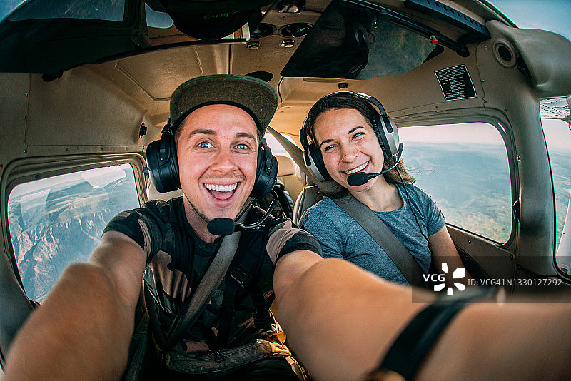 在小型单引擎飞机驾驶舱中一起飞行的两个快乐的年轻成年朋友图片素材