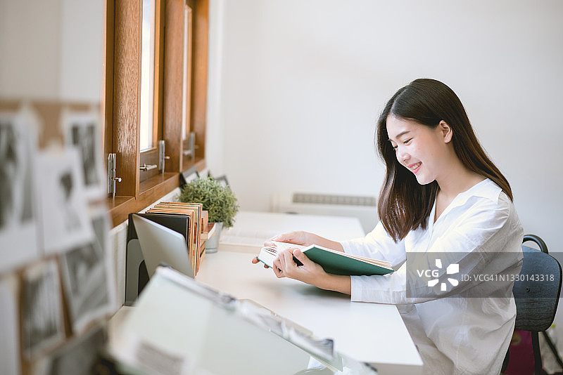 在家中窗边读书的年轻女子图片素材