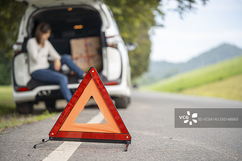 紧急停车标志和在路上抛锚的汽车与妇女图片素材