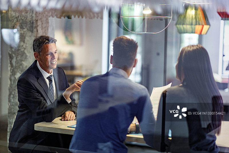 快乐的房地产商在办公室与夫妇会面图片素材